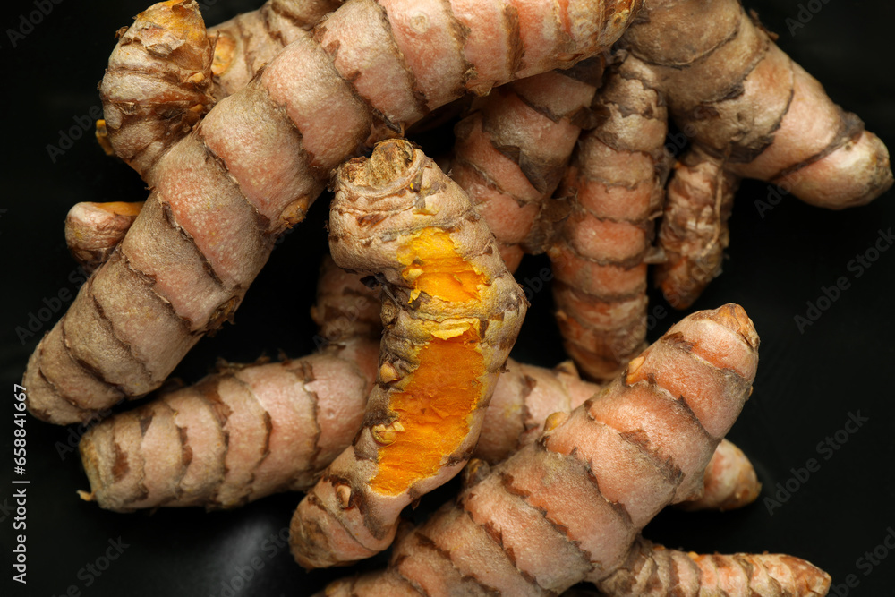 Many raw turmeric roots on black background, closeup Many raw turmeric roots on black background, closeup