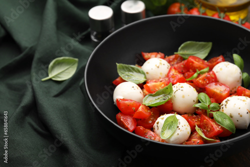 Tasty salad Caprese with tomatoes, mozzarella balls and basil on table, closeup. Space for text