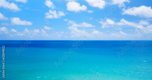 4K Aerial view Blue sky with white clouds moving panorama summer. Sea in light of day aerial view of drone slide forward. Small waves on sea. Sunny sunny over the sea. © BUDDEE