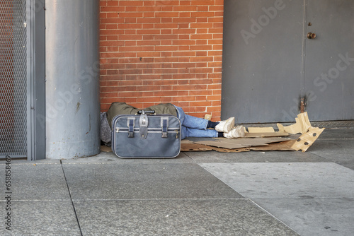 Slika na platnu A homeless man sleeping on cardboard on a street corner
