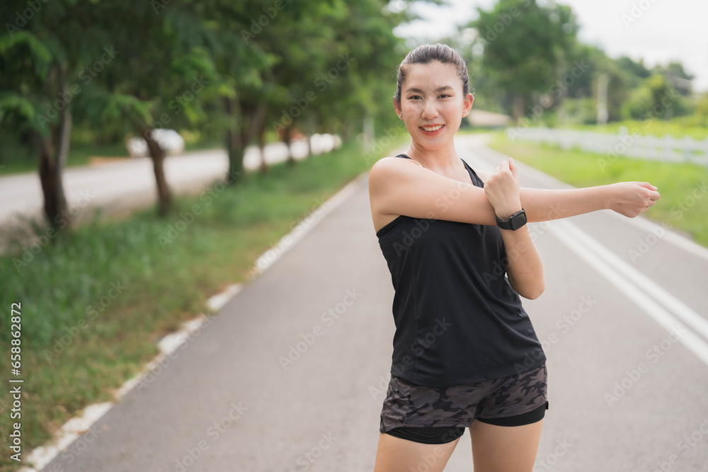 Asian woman wearing black exercise clothes is stretching and warming up before going for a run in the park. Healthy exercise concept. Body care, figure care. Asian woman wearing black exercise clothes is stretching and warming up before going for a run in the park. Healthy exercise concept. Body care, figure care.