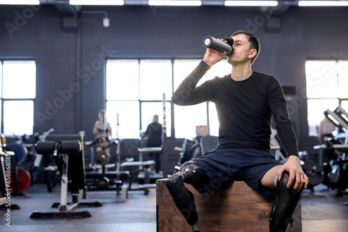 young tired man taking sip of water after difficult training. copy space. photo