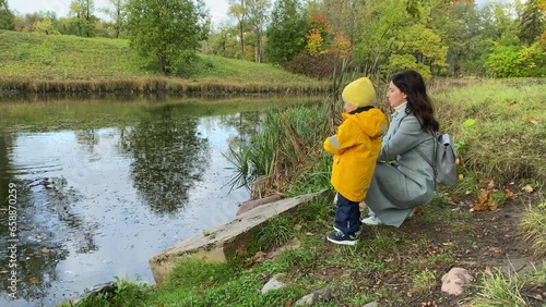 mother and toddler child feed wild ducks on pond in autumn park, Aleksandrovsky Park, Pushkin, St. Petersburg, Russia. photo