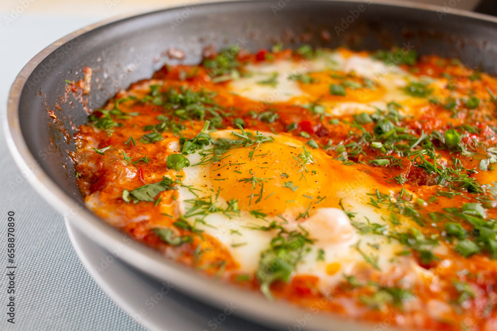 Shakshouka, eggs poached in sauce of tomatoes, olive oil, peppers, onion and garlic, Mediterranean cuisine.