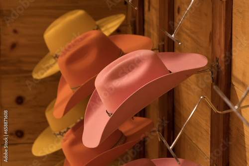 Pink and yellow cowgirl hats on hooks in a shop