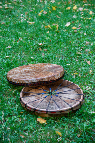 Two Shaman's tambourine made of genuine leather lie on the green grass.