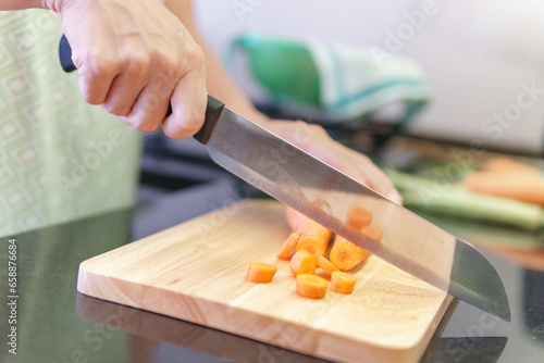 Woman hands cutting fresh orange carrots in a kitchen