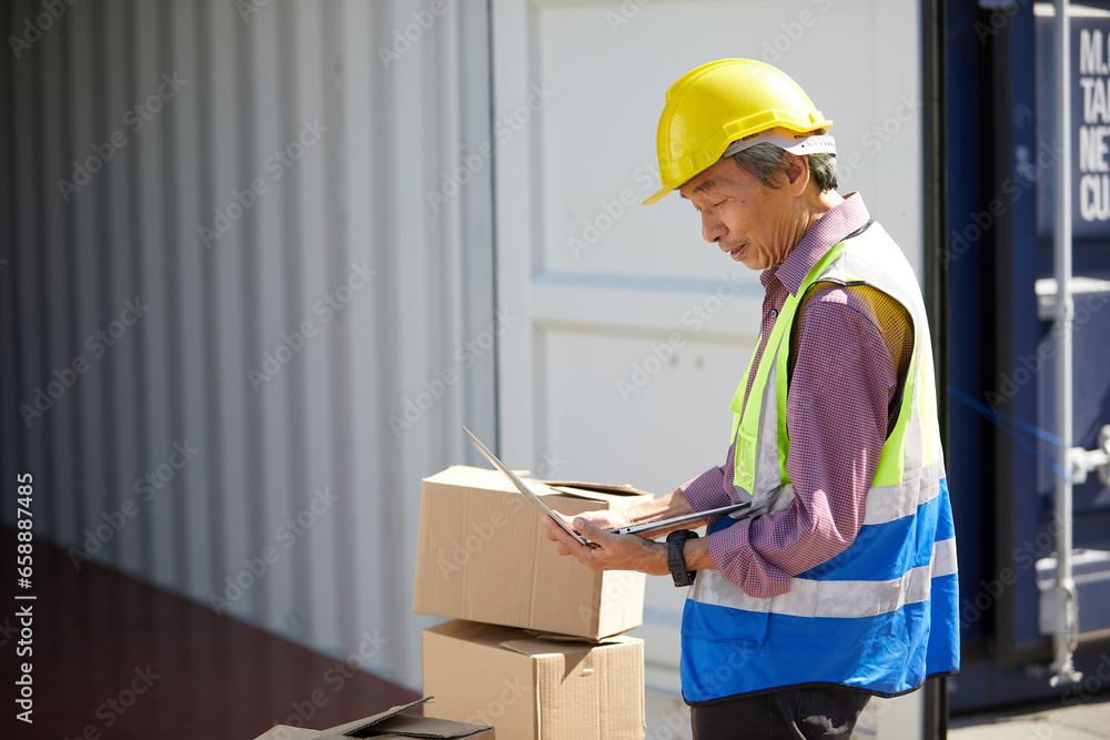 factory worker or engineer working on laptop computer and checking order in containers warehouse storage factory worker or engineer working on laptop computer and checking order in containers warehouse storage