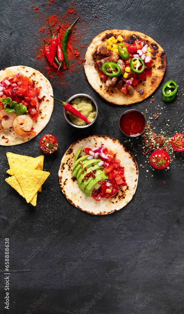 Tacos with salsa, vegetables and avocado on black background Tacos with salsa, vegetables and avocado on black background