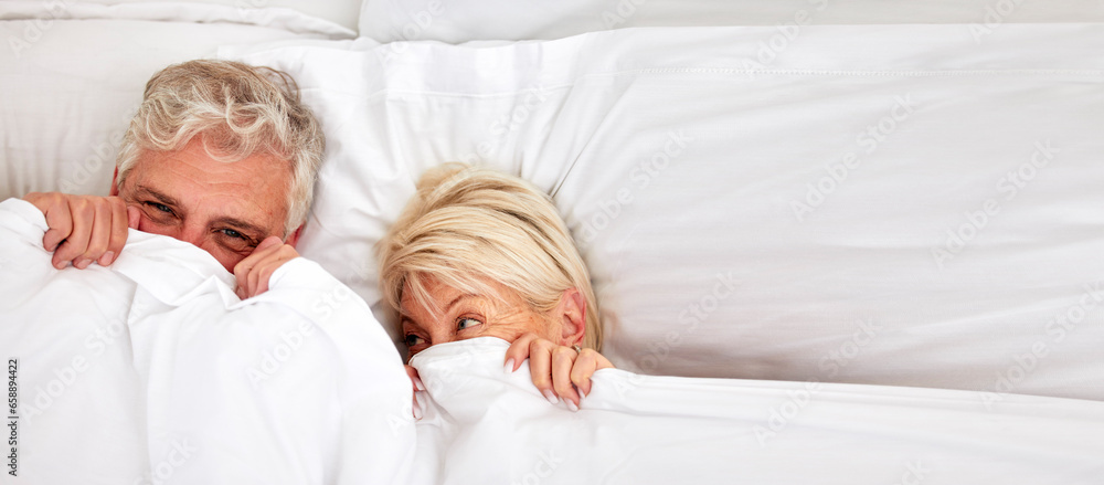 Senior couple, hiding and smile in bed for fun, comfort and bonding for love, silly and goofy together. Elderly people, marriage and sex in bedroom in retirement, romance and happiness at home Senior couple, hiding and smile in bed for fun, comfort and bonding for love, silly and goofy together. Elderly people, marriage and sex in bedroom in retirement, romance and happiness at home