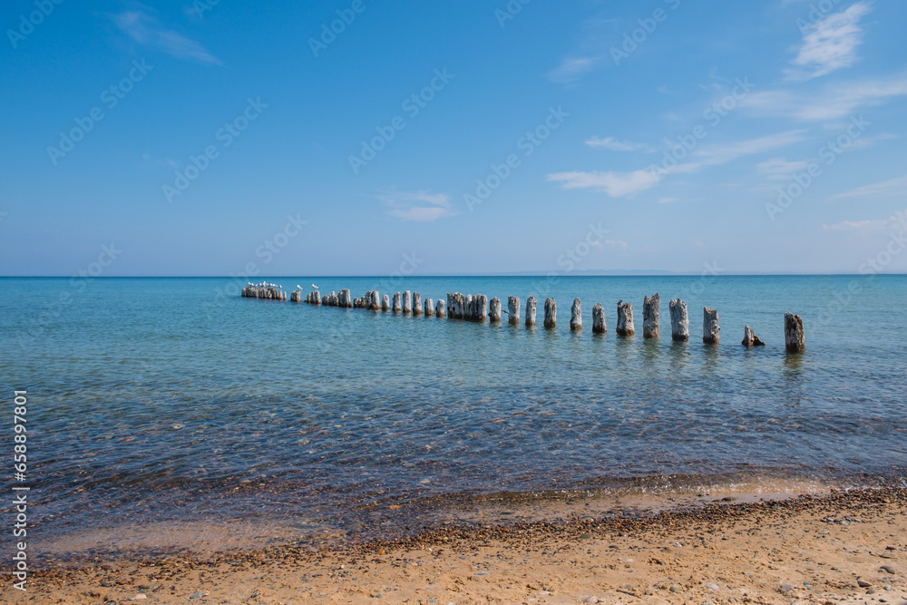 Clear blue waters of Lake Superior, with rocky beach and wooden pier.