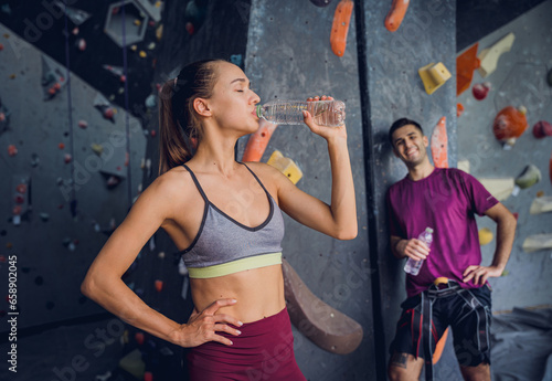 A strong couple of climbers against an artificial wall with colorful grips and ropes.