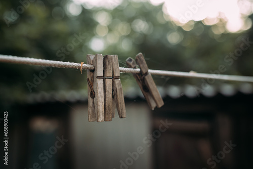 Isolated old wooden clothespins on the empty rope for drying clothes with blurry background. Concept of everyday household items