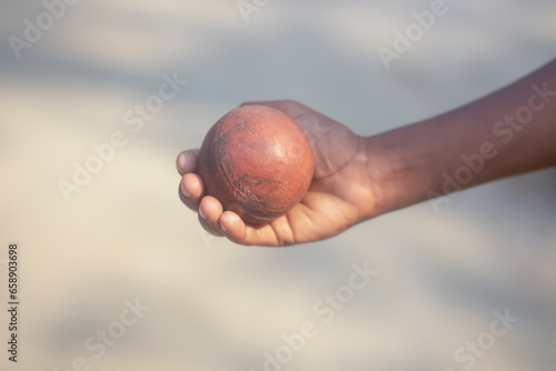 A boy is holding cricket ball with hand and blurred background