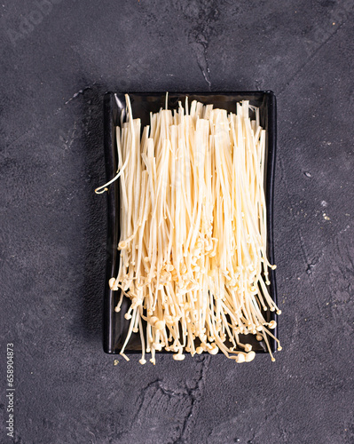 isolated enoki mushrooms called golden needle on a black plate.Chinese cuisine, hotpot ingredient