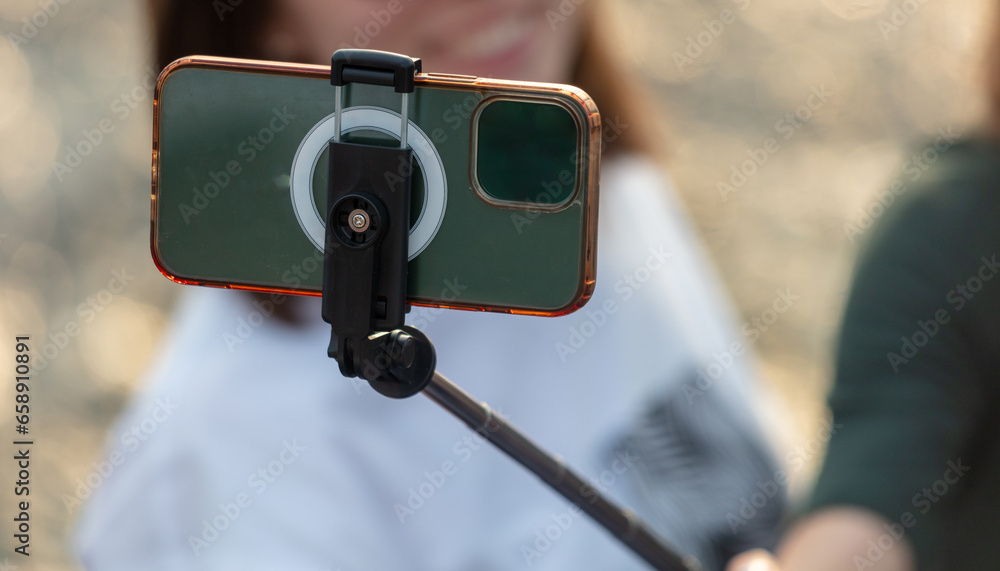 The smartphone takes photos using a selfie stick. Close-up The smartphone takes photos using a selfie stick. Close-up