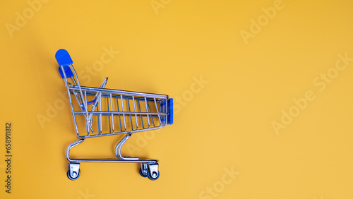 Shopping cart on yellow background with light and shadow. schopping concept.