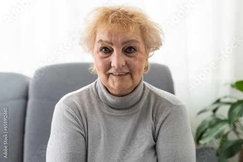 Happy cheerful elderly lady looking at camera with toothy smile, laughing, sitting on couch head shot portrait. Pretty senior woman talking on video call, enjoying conversation. Screen picture