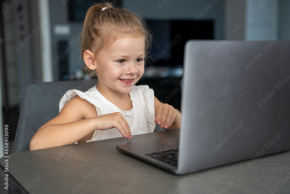 Little girl does finger gymnastics online on the laptop home. Distance learning concept. Little girl does finger gymnastics online on the laptop home. Distance learning concept.
