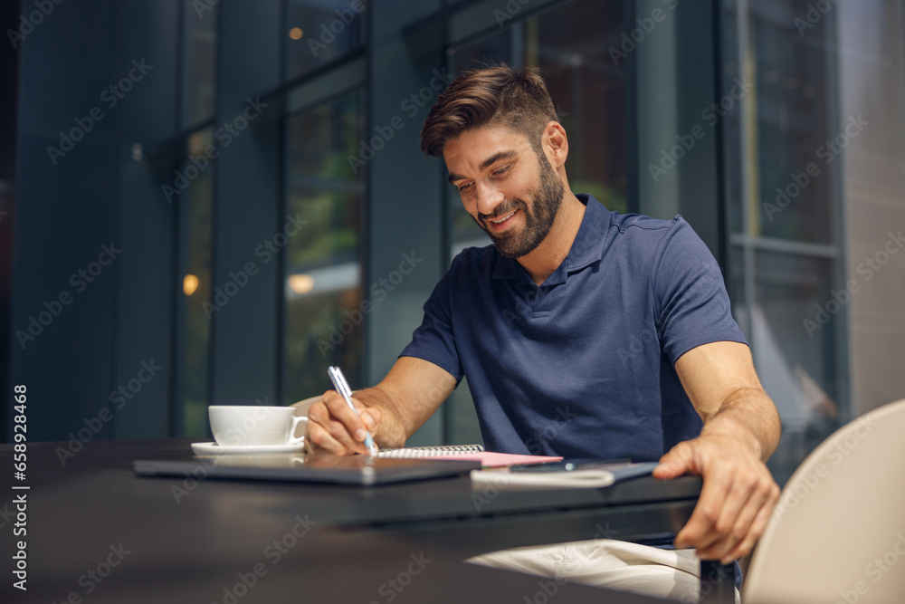 Male manager making notes in notepad during working day in modern office Male manager making notes in notepad during working day in modern office
