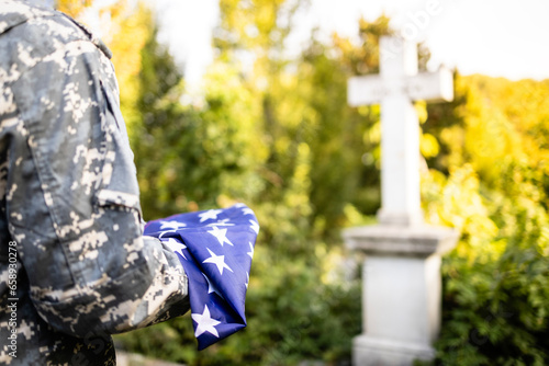 Soldier holding folded American flag on Memorial Day at cemetery. Respecting those who gave life for the USA. photo