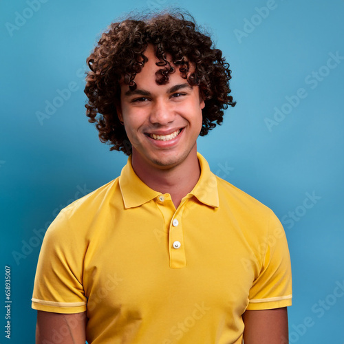 Happy curly hair man smiling and laughing, wearing a yellow t shirt on a bright solid blue background. created by generative AI technology