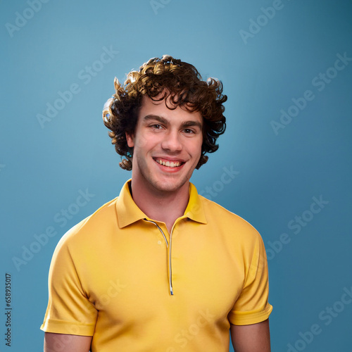 Curly hair man smiling and laughing, wearing a yellow t shirt on a bright solid blue background. created by generative AI technology