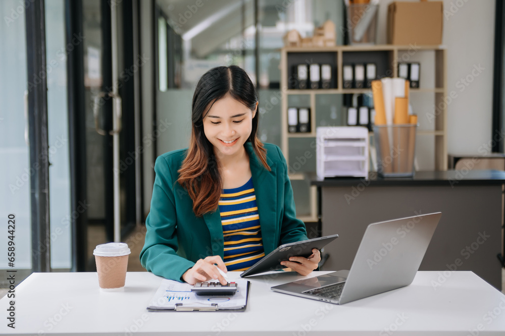 Confident business expert attractive smiling young woman typing laptop ang holding digital tablet on desk in office. Confident business expert attractive smiling young woman typing laptop ang holding digital tablet on desk in office.