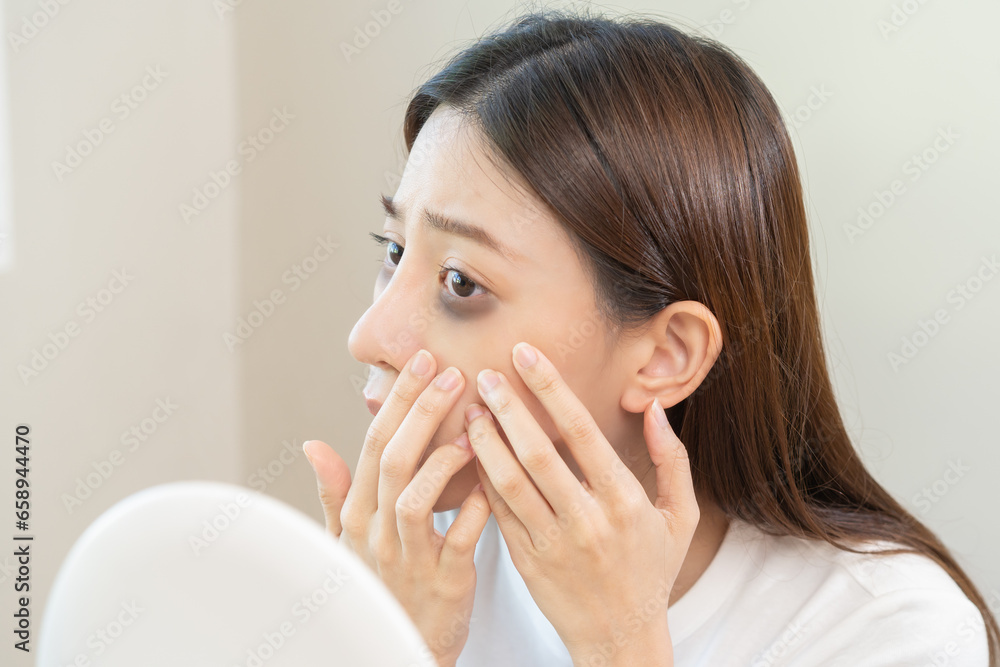 Bored, insomnia asian young woman, girl looking at mirror hand touching under eyes with problem of black circles or panda puffy, swollen and wrinkle on face. Sleepless, sleepy healthcare person. Bored, insomnia asian young woman, girl looking at mirror hand touching under eyes with problem of black circles or panda puffy, swollen and wrinkle on face. Sleepless, sleepy healthcare person.