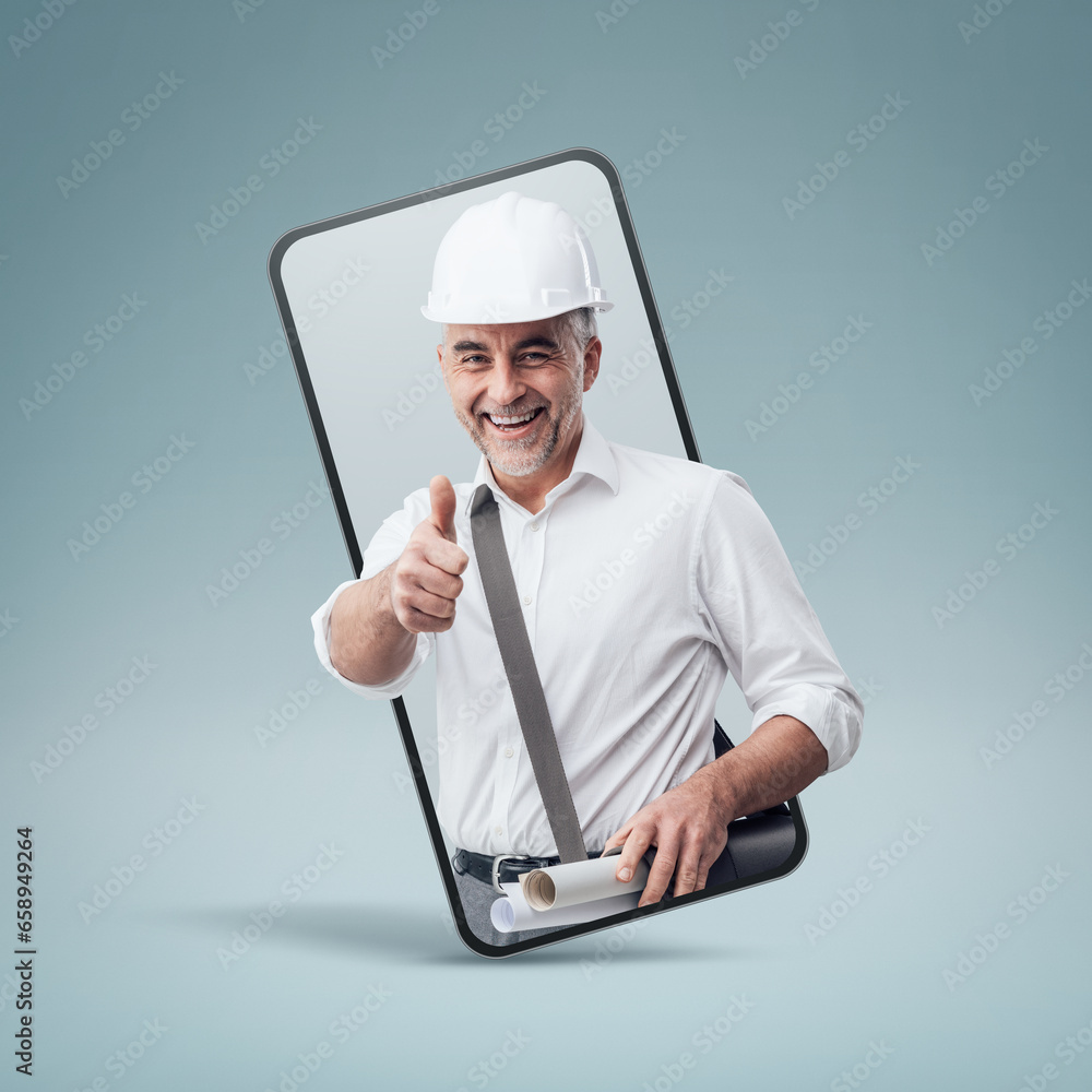 Cheerful construction engineer giving a thumbs up in a smartphone videocall and smiling, online service concept Cheerful construction engineer giving a thumbs up in a smartphone videocall and smiling, online service concept