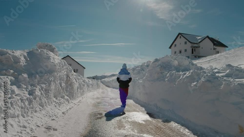 Large view of tourist female coming back to the chalet after morning walk. No traffic cleared of snow road perfect for walking for travelers.