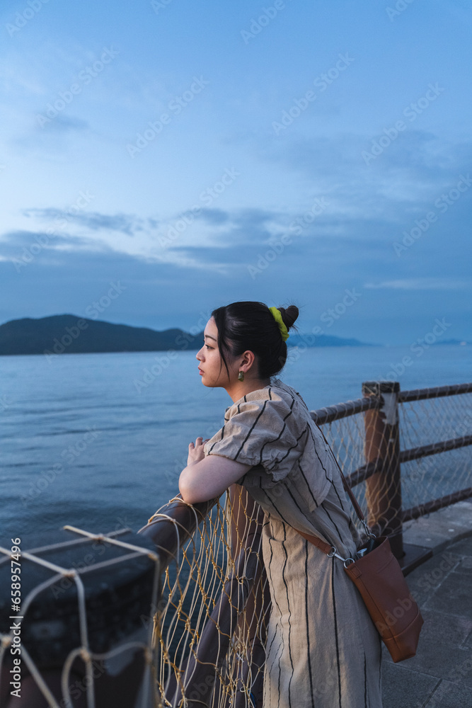 Obraz premium 夕暮れの海にいる女性