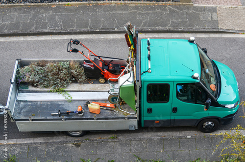 Konzept Hausmeister- und Gartenservice: Rasenmäher, Schiebkarre, Besen, Rechen, Schaufeln und andere Werkzeuge für Haus und Garten auf der Ladefläche eines Transporters, Luftaufnahme, Copy space