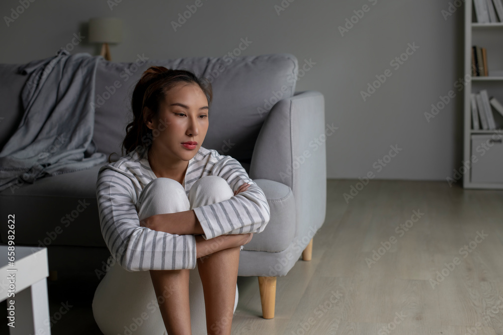 Lonely Asian woman in distress, worried, confused, sitting on floor at home. Female suffer from mental health problems. Lonely Asian woman in distress, worried, confused, sitting on floor at home. Female suffer from mental health problems.
