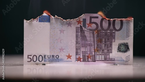 The euro is slowly smoldering. Cash is not used in everyday life. The euro is falling. The 500 euro bill is slowly smoldering from the fire.