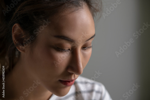Close-up of an Asian woman's face in a distressed mood, sad, worried, disappointed, lonely from mental illness while at home. Female suffer from mental health problems.