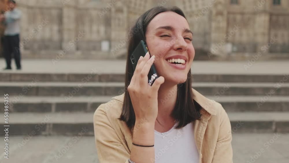 Close up, woman traveler talking on mobile phone while sitting on steps of old building Close up, woman traveler talking on mobile phone while sitting on steps of old building