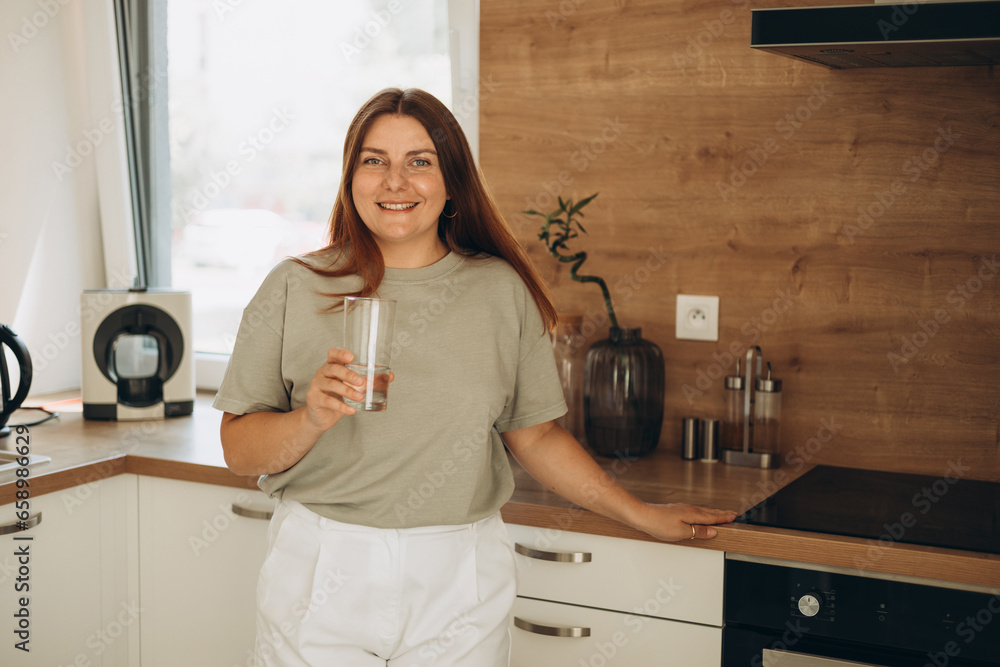 Healthy lifestyle. Portrait of happy young Woman with Glass of fresh water in kitchen. Healthcare. Drinks. Health, Beauty, Diet concept. Healthy lifestyle. Portrait of happy young Woman with Glass of fresh water in kitchen. Healthcare. Drinks. Health, Beauty, Diet concept.