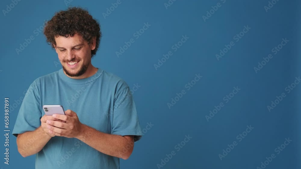 Smiling man holding phone c mockup space in studio on blue background Smiling man holding phone c mockup space in studio on blue background