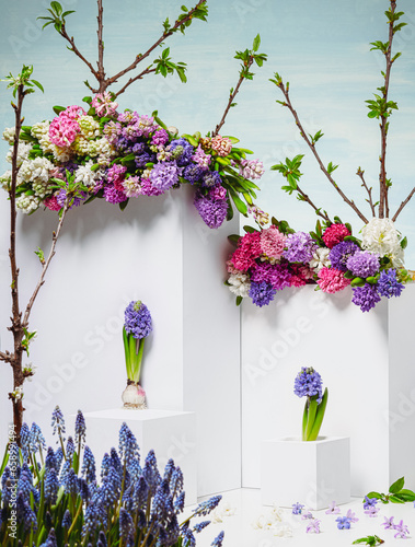 A composition of fresh flowers and white cubes against a blue sky background.