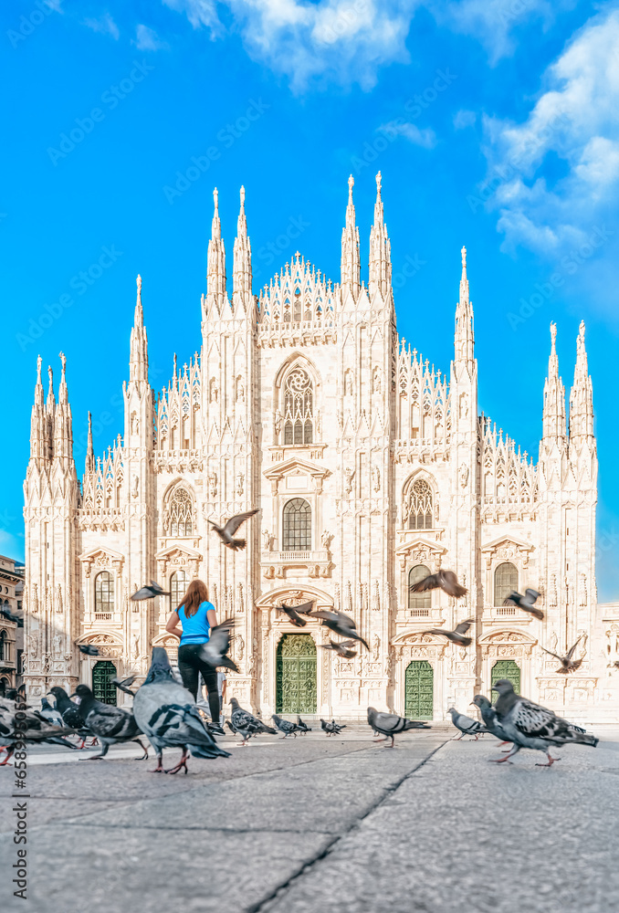 Italy - Milan Duomo cathedral at sunny day - Traveler woman feeds pigeons in the square-  Doves flying at Milano Piazza - Travel destinations