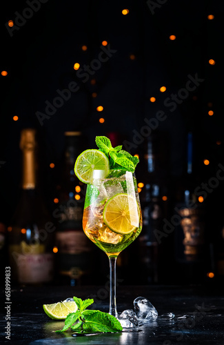Hugo spritz cocktail drink with sparkling wine, elderflower syrup, soda, lime, mint and ice, dark bar counter background
