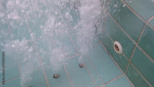 Close up, underwater, air bubbles from jacuzzi spa jet in swimming pool.