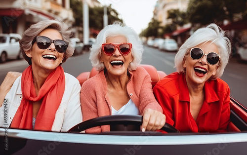 Company of three elderly girlfriends of pensioners ride a cabrio car together and have fun photo