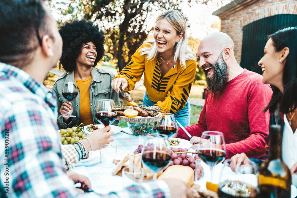Obraz premium Happy friends having bbq dinner party at backyard -Multiracial young people eating food and drinking red wine in garden restaurant