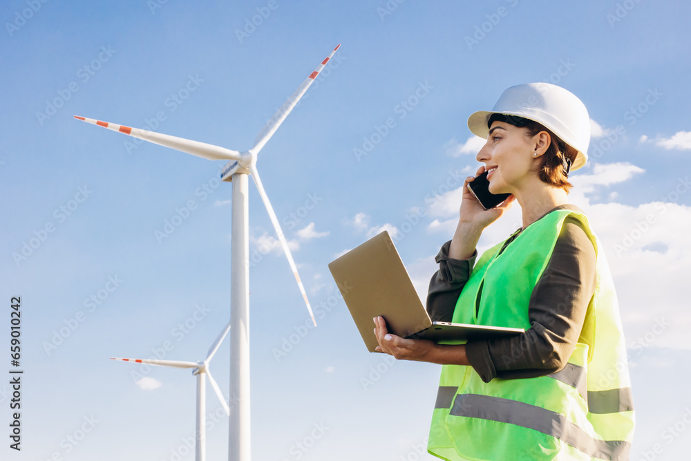 Woman with laptop having online conference by the windmill turbines Woman with laptop having online conference by the windmill turbines