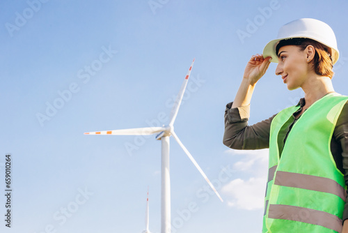 Portrait of woman engineer standing by the windmill turbines