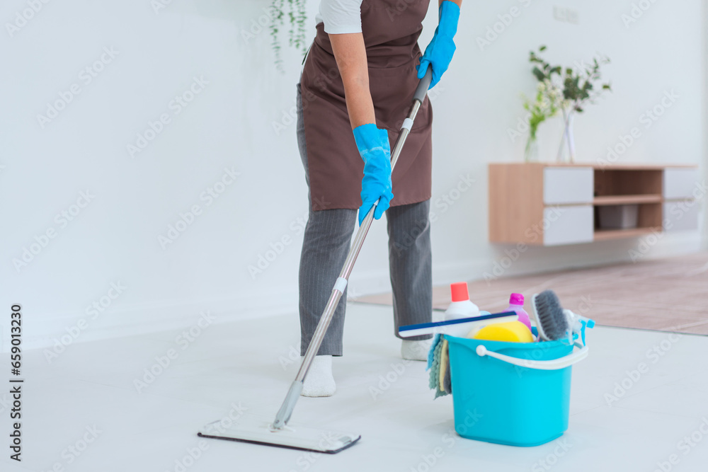 Maid using mop with bucket plastic of cleaner equipment to mopping cleanup floor in living room Maid using mop with bucket plastic of cleaner equipment to mopping cleanup floor in living room