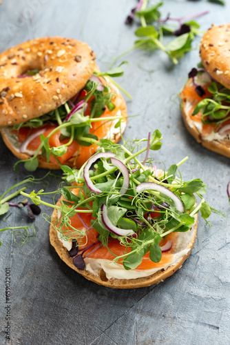 Smoked salmon and soft cheese seeded bagel with pea and purple reddish shoot salad and red onion. Protein packed breakfast concept photo