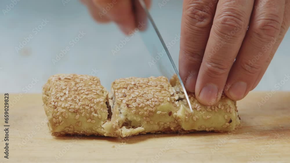 Confectioner cuts freshly baked baklava with a knife on a wooden board Confectioner cuts freshly baked baklava with a knife on a wooden board